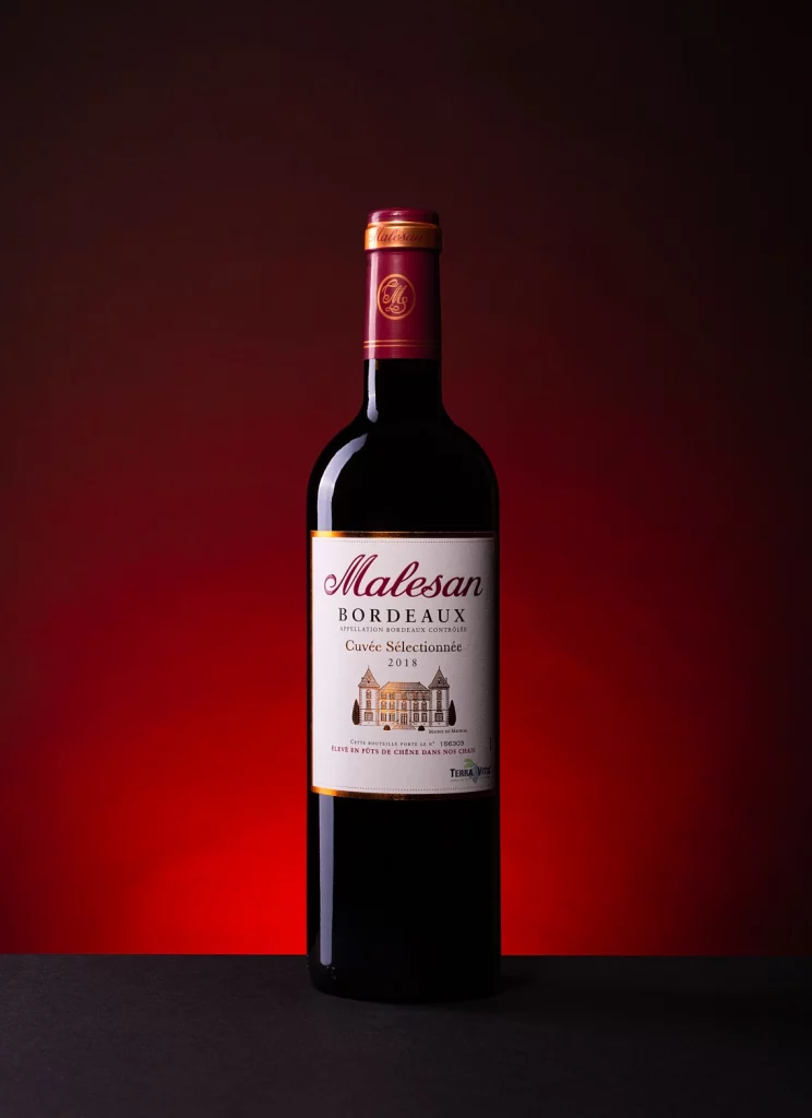 Photographie d'une bouteille de vin rouge bordeaux sur fond noir et halo rouge - Photographe publicitaire boissons - photographe bouteille de vin - photographe commercial - Aurore Aivrest