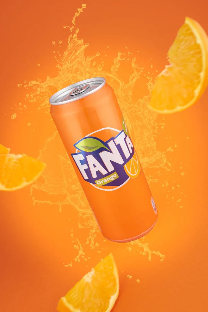 Photographie d'une canette de soda à l'orange qui vole avec des quartiers d'orange, sur un fond orange - Photographe publicitaire boissons - photographe e-commerce - photographe commercial - Aurore Aivrest