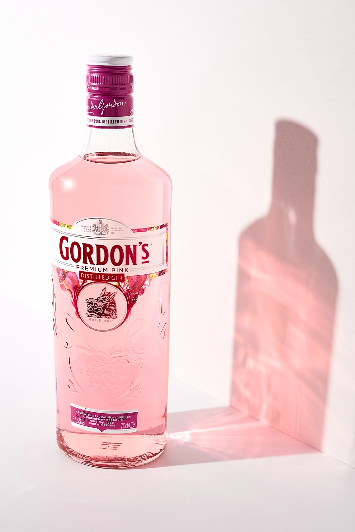 Photographie d'une bouteille de gin rose sur un fond blanc, avec son ombre de lumière - Photographe publicitaire boissons - photographe e-commerce - photographe commercial - Aurore Aivrest