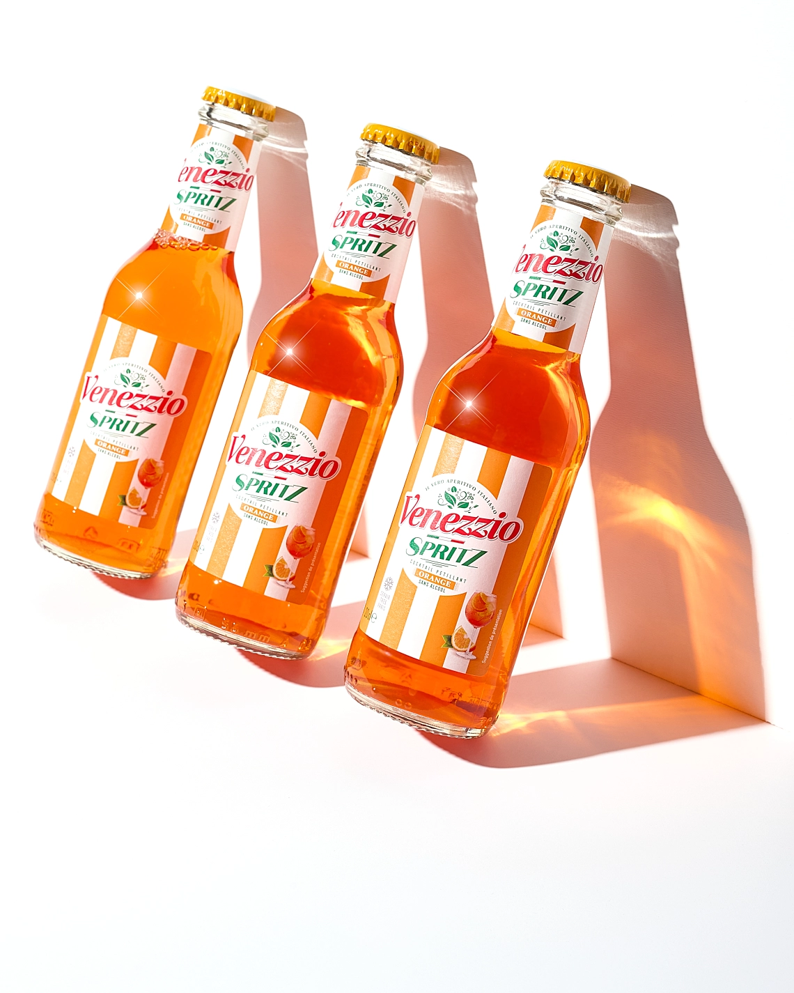 Photographie de trois bouteilles de spritz adossées contre un mur blanc, avec leur ombre de lumière - Photographe publicitaire boissons - photographe e-commerce - photographe commercial - Aurore Aivrest