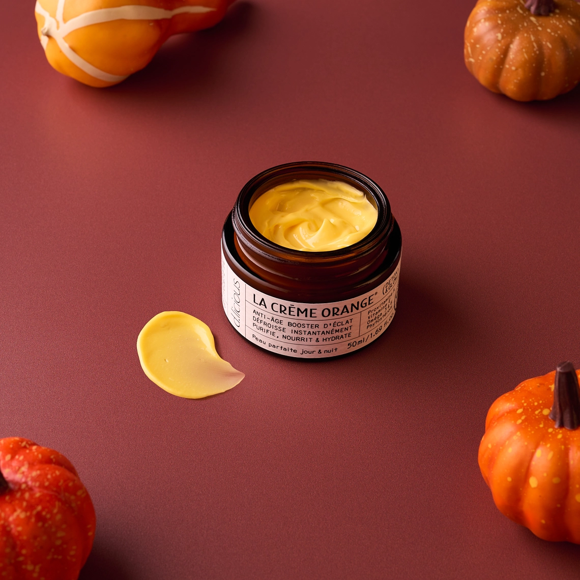 Photographie d'une creme pour le visage et de couleur orange, dans une mise en scene sur le theme de l'automne, dans une ambiance orangé, marron. Avec des courges, citrouilles - Photographe cosmetiques - photographe reseaux sociaux - photographe produits cosmetiques - photographe publicitaire cosmetiques - Aurore Aivrest