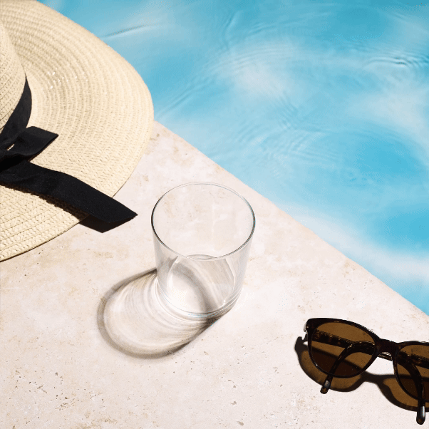 Stop motion video d'un verre se remplissant au fur et a mesure, puis se vidant au fur et a mesure, sur le rebord en travertin d'une piscine , avec un chapeau de paille et des lunettes de soleil - Photographe publicitaire boissons - photographe stop motion boissons - photographe stop motion - Aurore Aivrest