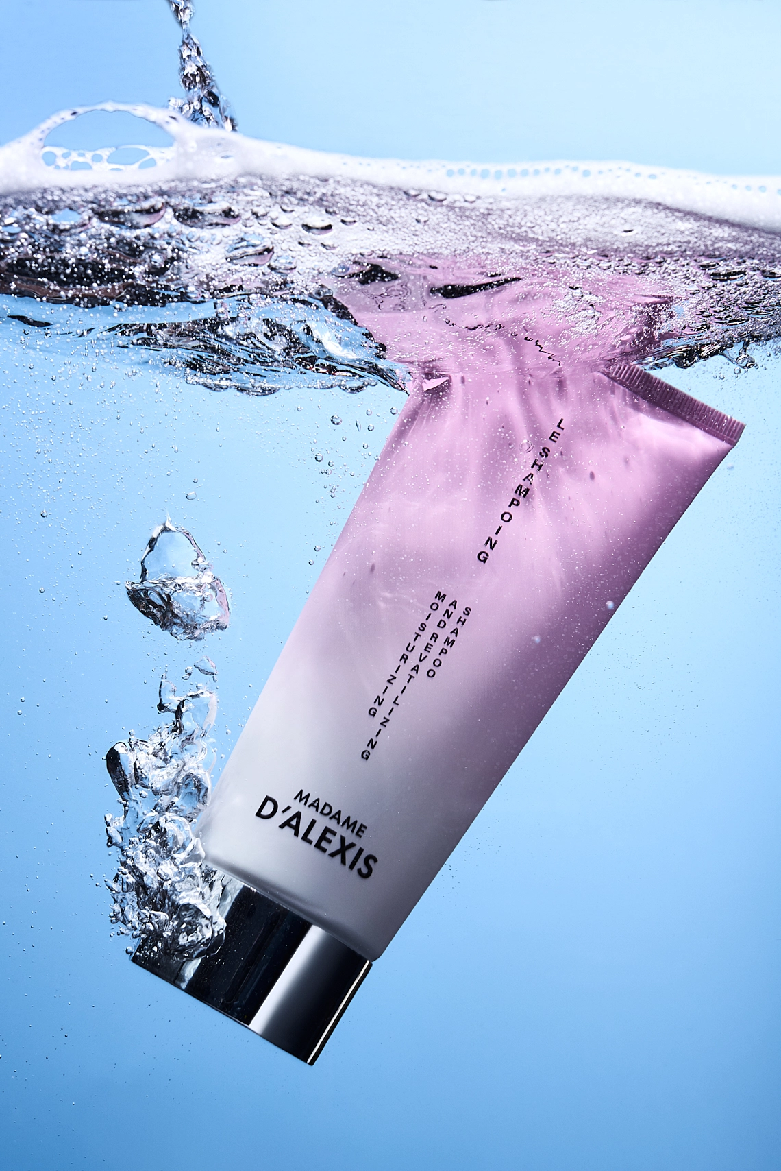 Photographie d'un tube de shampooing rose et blanc qui tombe dans l eau. On voit egalement de la mousse du produit en surface. Le tout est sur un fond bleu ciel imitant le bleu de l eau. Le rendu est moderne et dynamique - Photographe cosmetiques - photographe publicitaire cosmetiques - photographe produits cosmetiques - Aurore Aivrest