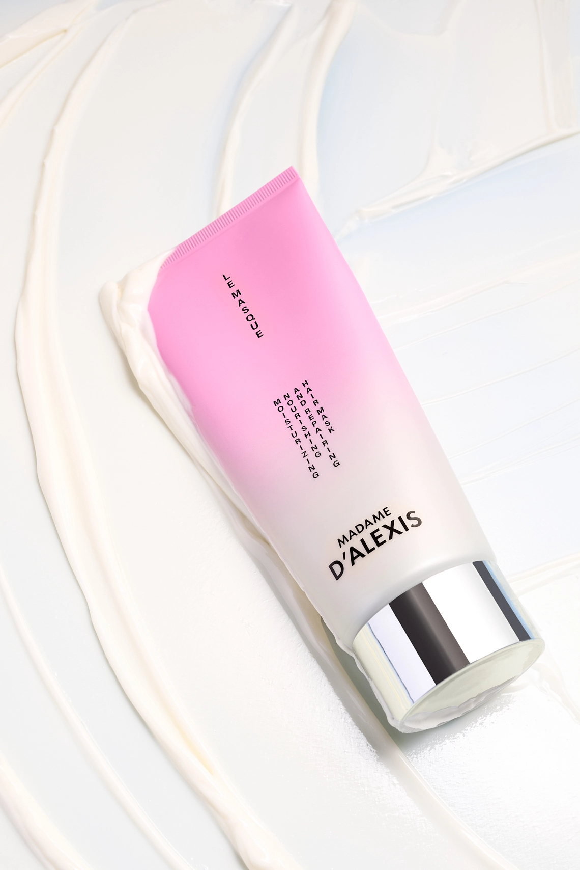 Photographie d'un tube de masque capillaire rose et blanc qui glisse dans sa propre texture. En effet le fond est compose du masque qui a ete etale sur le fond bleu et vient totalement le recouvrir. Fond texture sur lequel vient glisser le tube couche. - Photographe cosmetiques - photographe publicitaire cosmetiques - photographe produits cosmetiques - Aurore Aivrest